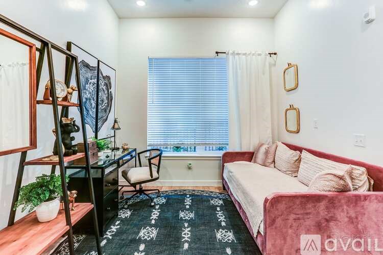 A living room with a red couch and a black and white rug.