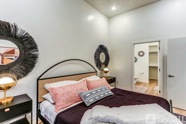 A bedroom with a bed, a lamp, and a mirror on the wall.