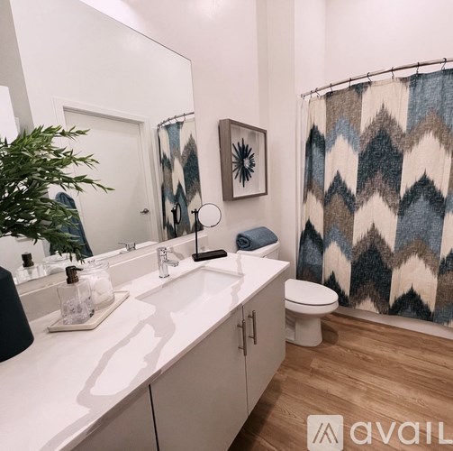 A bathroom with a white counter top and a blue and white shower curtain.