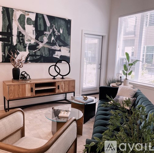 A living room with a black couch and a large abstract painting on the wall.