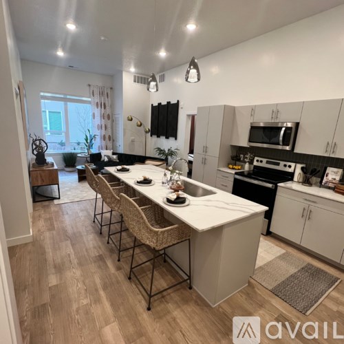 A kitchen with a long white island and chairs.
