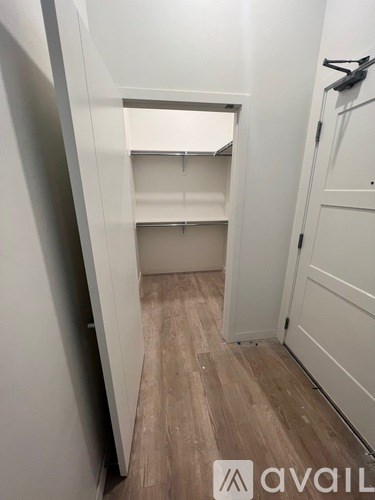 A white closet with a wooden floor and shelves.