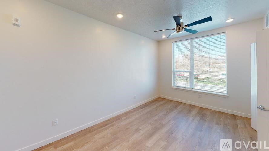 A room with a ceiling fan and a window with blinds.