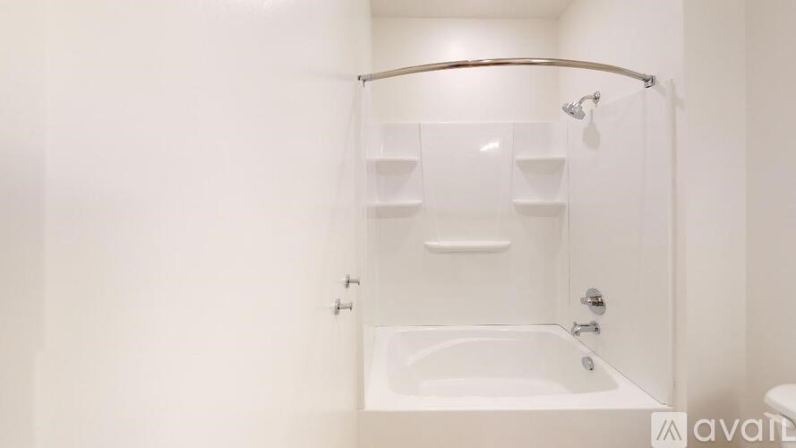 A white bathroom with a tub and shelves.