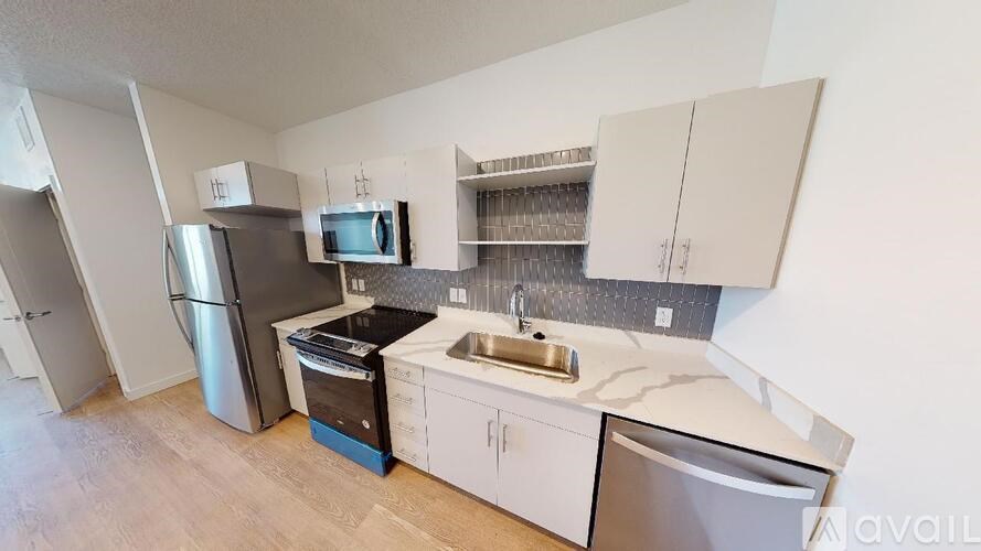 A kitchen with a refrigerator, microwave, and sink.