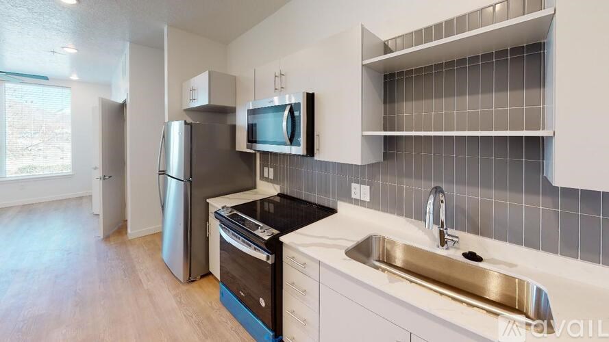 A kitchen with a refrigerator, microwave, oven, and sink.