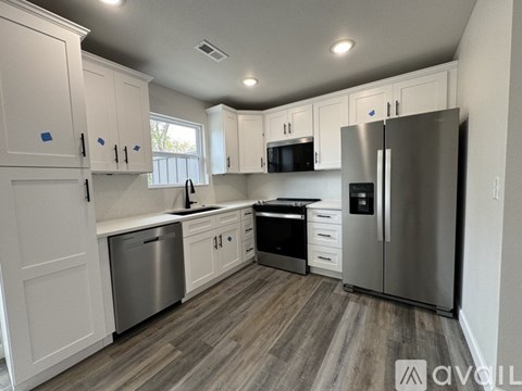 A kitchen with white cabinets and a stainless steel refrigerator.