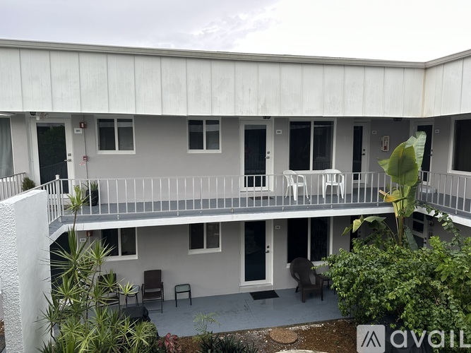 A white building with a balcony and chairs.
