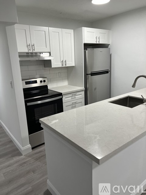 A kitchen with white cabinets and a marble countertop.