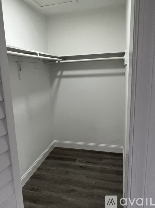 A small, empty room with a wooden floor and white walls.