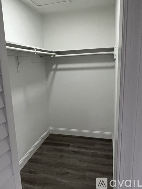 A small, empty room with a wooden floor and white walls.