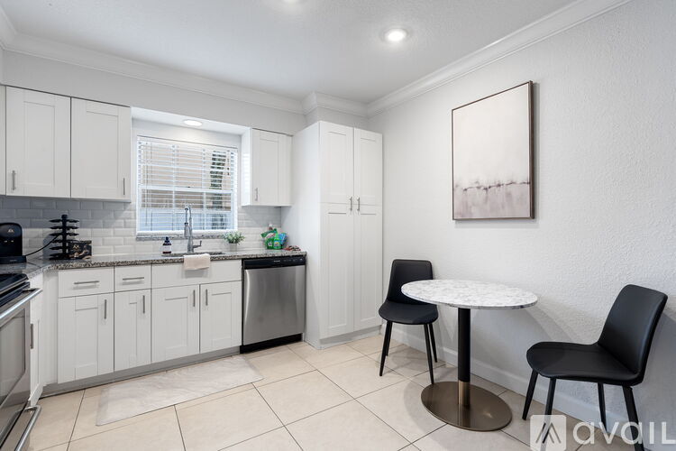 A kitchen with white cabinets and a black chair.