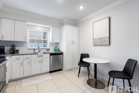 A kitchen with white cabinets and a black chair.