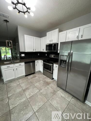 A kitchen with white cabinets and a tiled floor.