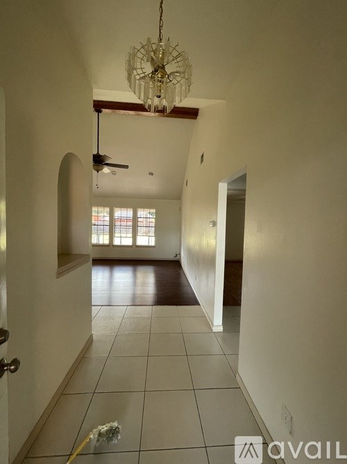 A hallway with a chandelier and a broom on the floor.