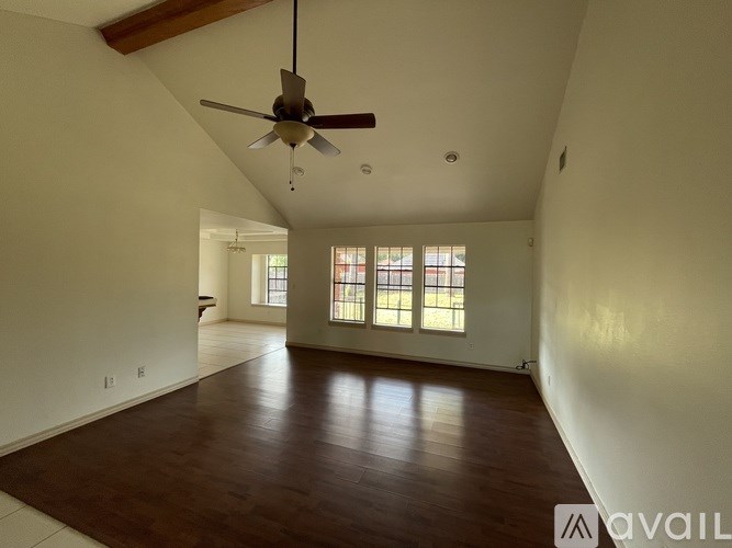 A spacious room with a ceiling fan and wooden flooring.