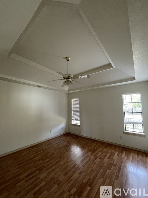 A room with a ceiling fan and wooden flooring.