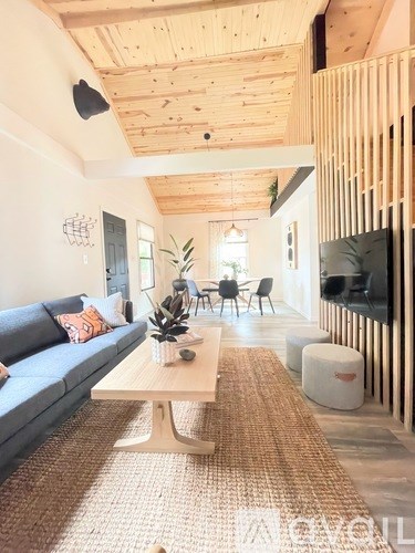 A living room with a blue couch and a wooden ceiling.