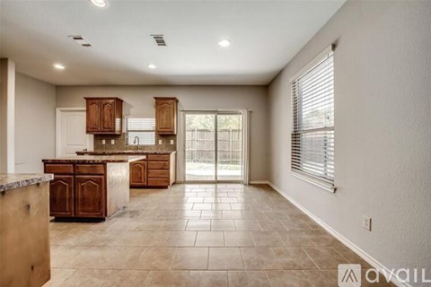 A spacious kitchen with wooden cabinets and a tiled floor.