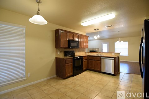 A kitchen with wooden cabinets and a black refrigerator.