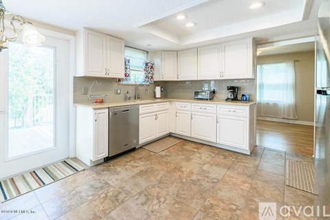 A kitchen with white cabinets and a tiled floor.