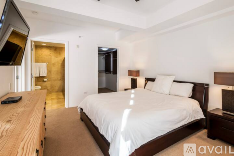 A bedroom with a large bed and a wooden dresser.