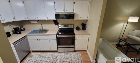 A kitchen with white cabinets and a patterned rug on the floor.