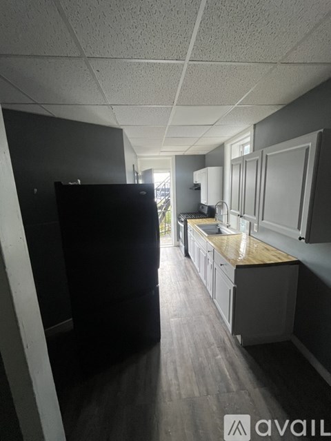 A kitchen with a black refrigerator and wooden floors.