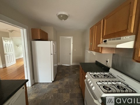 A kitchen with a white stove and wooden cabinets.
