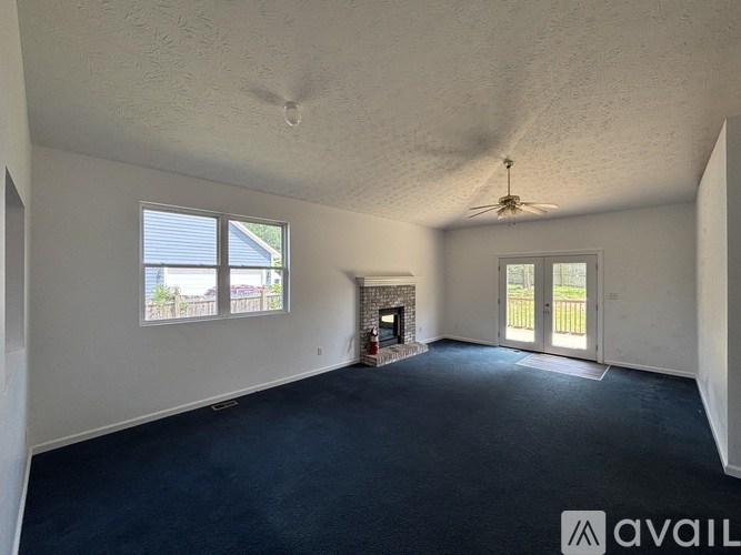 A spacious room with a fireplace and a ceiling fan.