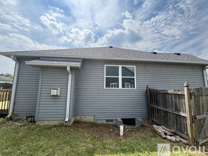 A grey house with a wooden fence in front.