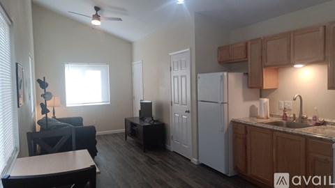 A kitchen with a refrigerator, sink, and cabinets.