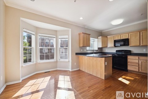 A kitchen with wooden cabinets and black countertops is available for rent.