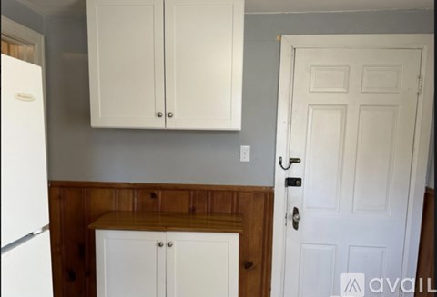 A kitchen with white cabinets and a white door.