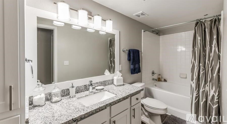 A bathroom with a large mirror, a sink, a toilet, and a shower.