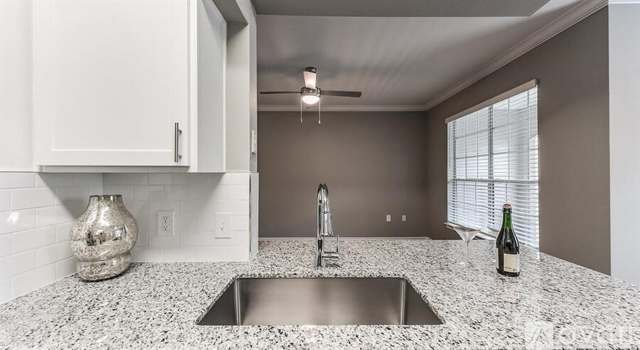 A kitchen with a granite countertop and a stainless steel sink.
