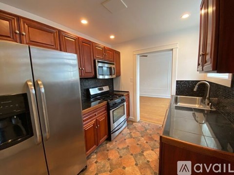 A kitchen with a refrigerator, microwave, oven, sink and cabinets.