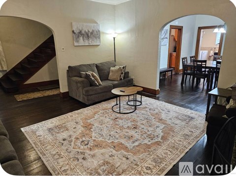 A living room with a grey couch and a rug.