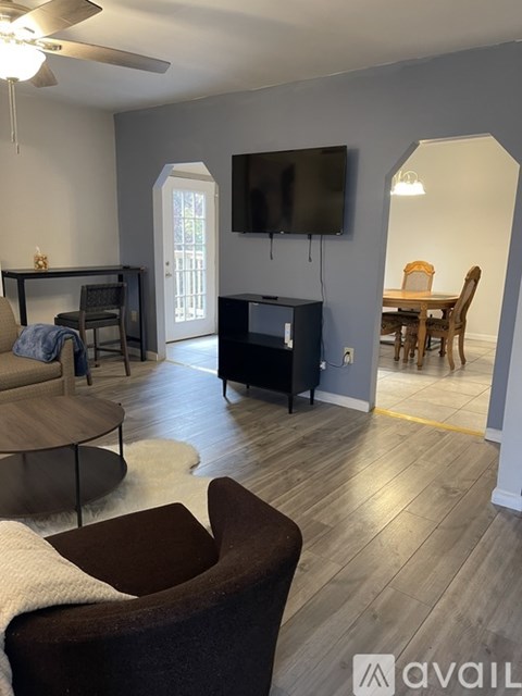 A living room with a brown chair and a television mounted on the wall.