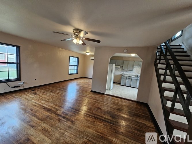 A spacious room with wooden floors and a ceiling fan.