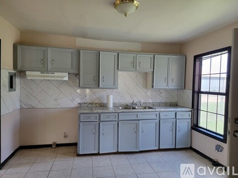 A kitchen with grey cabinets and a marble countertop.