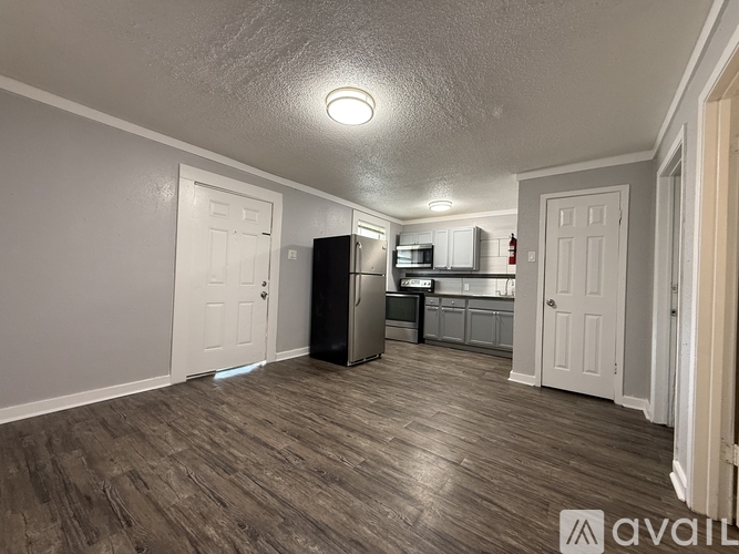 A spacious room with wooden flooring and a white refrigerator.