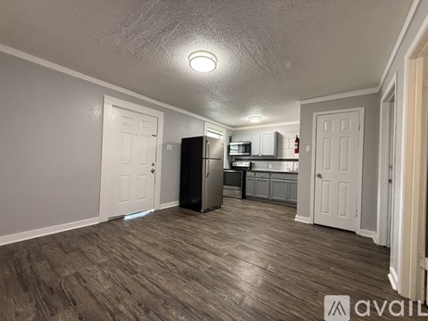 A spacious room with wooden flooring and a white refrigerator.