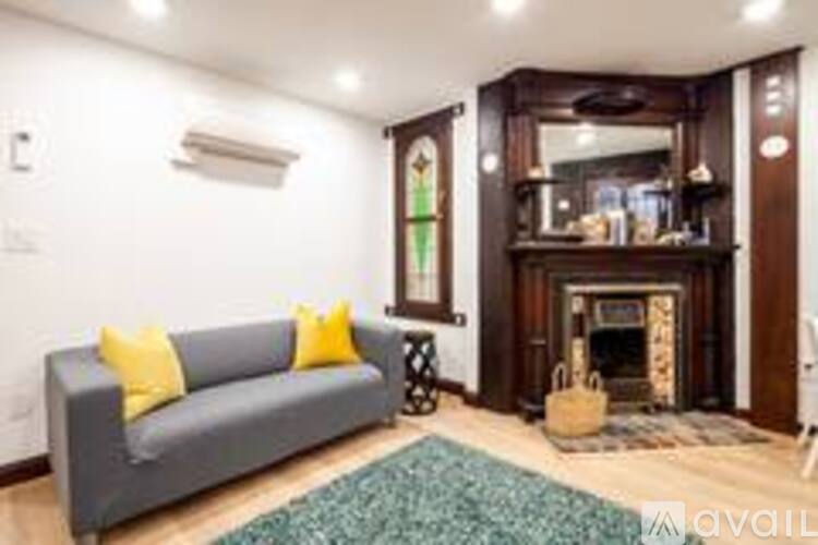 A grey couch with yellow pillows sits in a room with a fireplace.