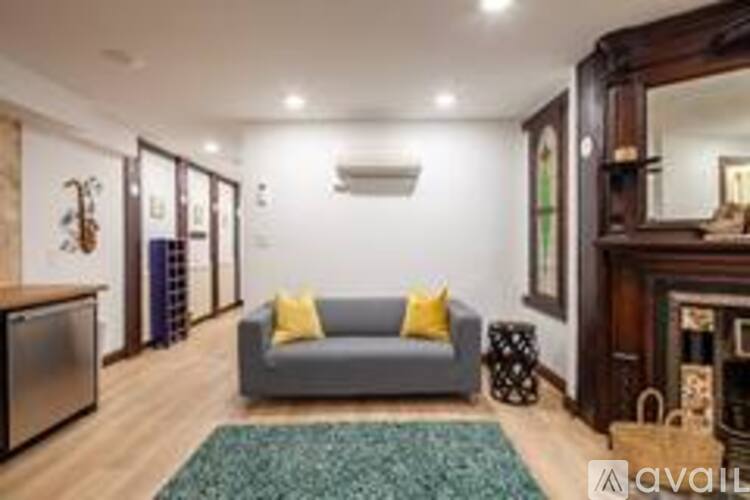 A living room with a grey couch and a green rug.