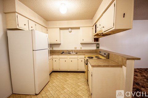 A kitchen with a white refrigerator and cabinets.