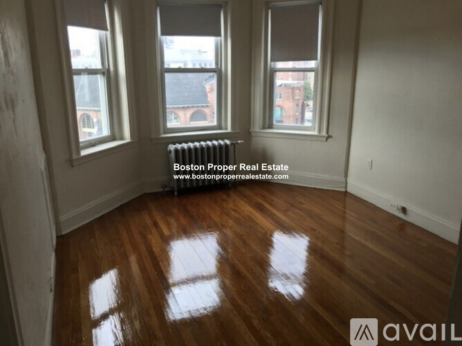 A room with wooden floors and three windows.