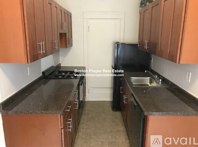 A kitchen with brown cabinets and a black refrigerator.