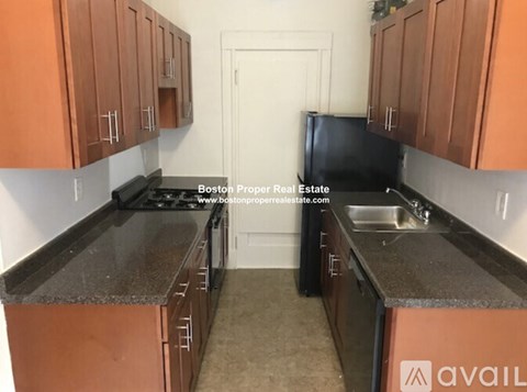 A kitchen with brown cabinets and a black refrigerator.