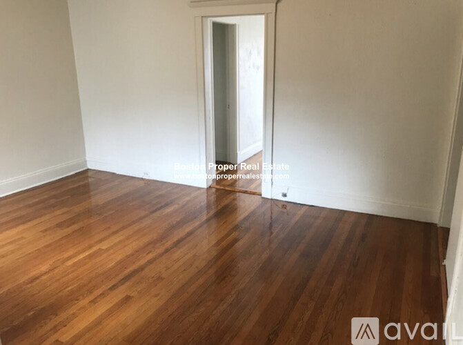 A room with wooden flooring and a doorway leading to another room.